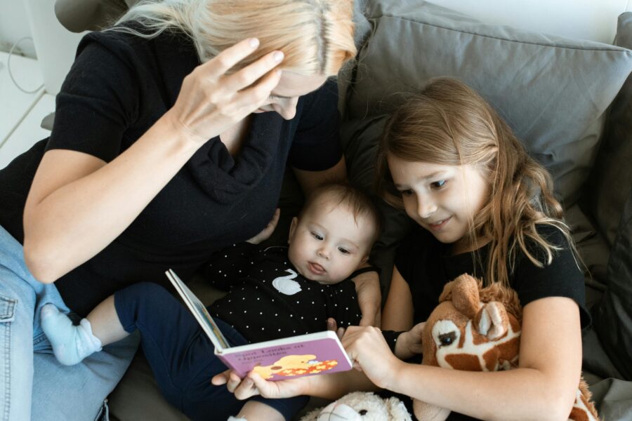 En mamma ligger i sängen och läser bok med sina två barn. Dags för vabb igen.