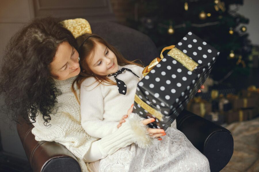 En mamma som sitter med sin dotter och håller ett paket. Hon inser det viktiga under all julstress.