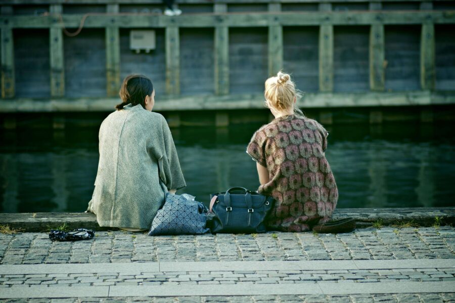 Två tjejer som sitter vid vattnet. De upplever att de har olika behov i en relation.